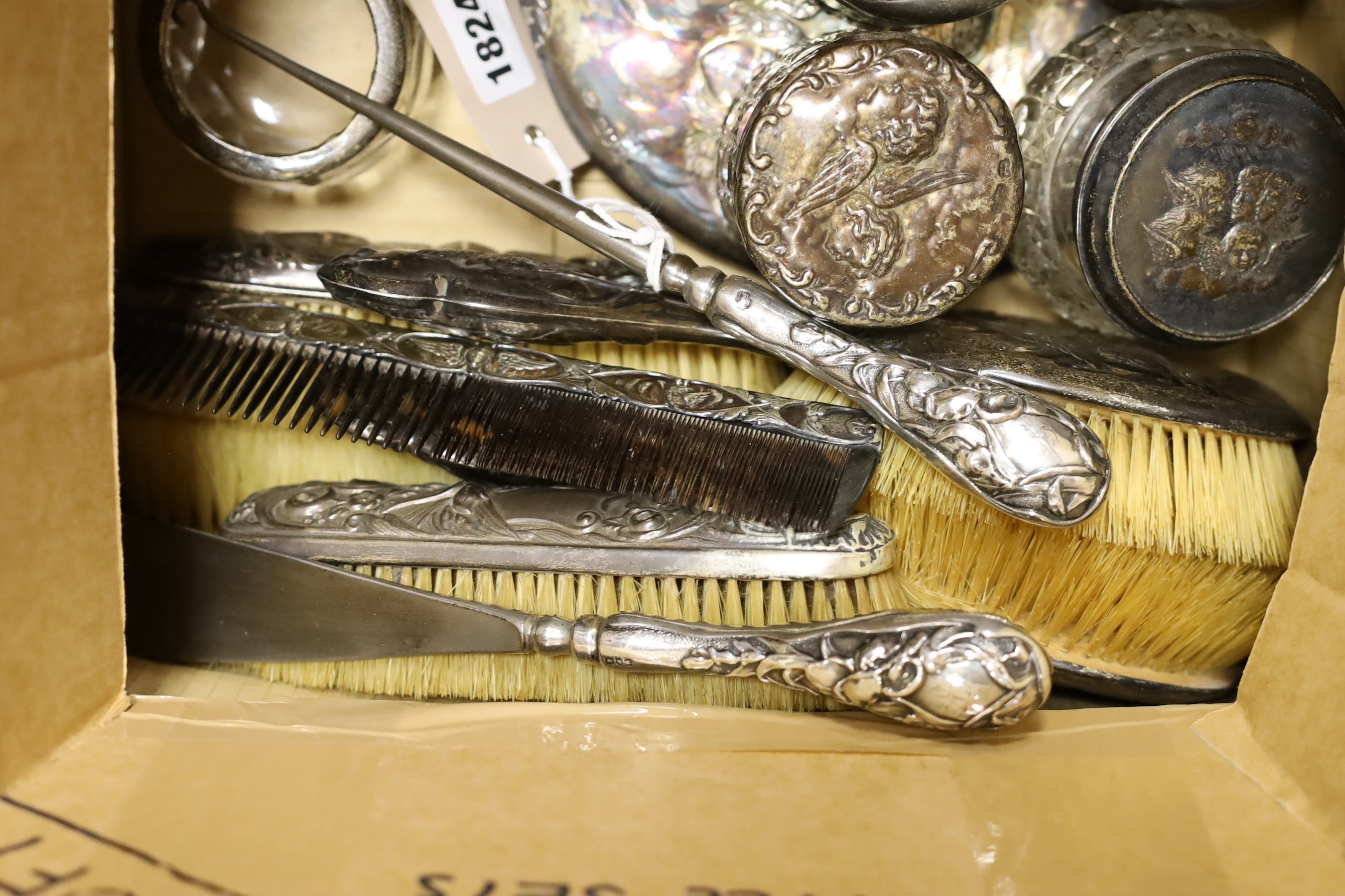 A late Victorian five piece silver Reynolds angel dressing table set, maker William Comyns, four assorted silver lidded glass Reynolds angel toilet jars and sundries